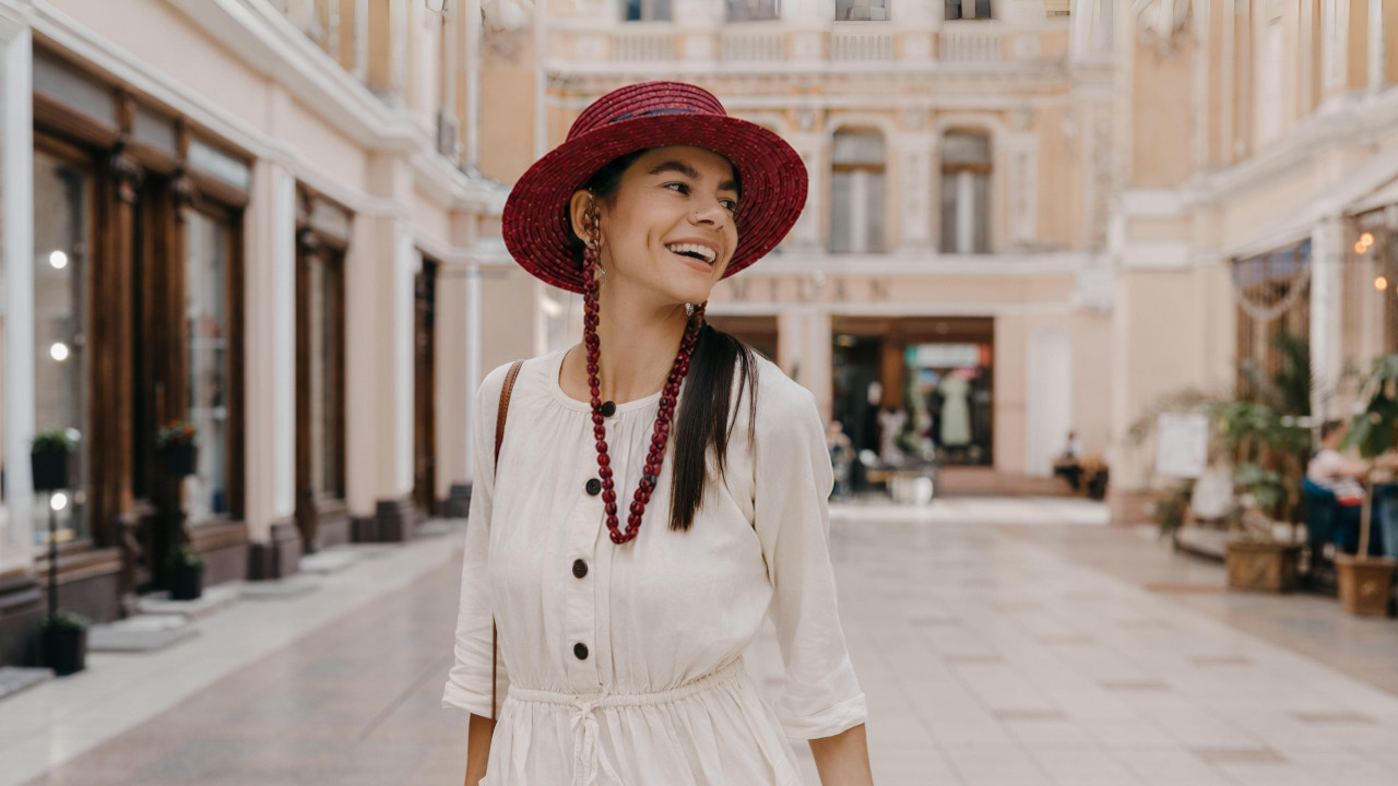 A woman in a white dress and red hat strolls through an empty mall, showcasing a serene shopping environment.