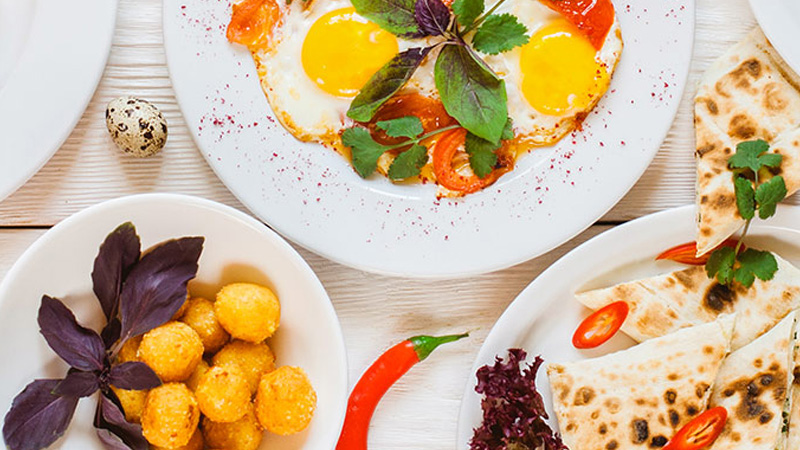 A table set with a variety of foods, including eggs, potatoes, and bread, arranged for a meal.