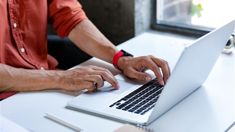 A man focused on typing on a laptop computer, with his hands positioned over the keyboard. image