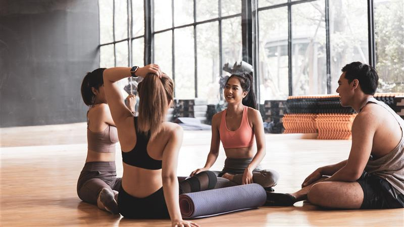 A group of individuals seated on the floor, engaged in a yoga class, practicing mindfulness and relaxation techniques.